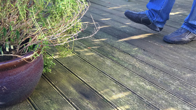 man standing on wooden decking with slippery moss slippery decking with moss